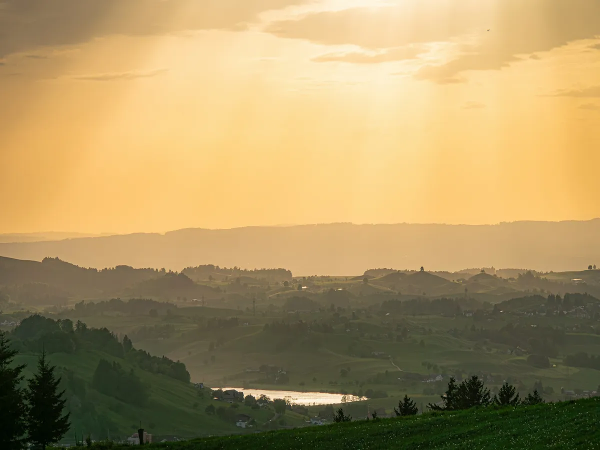 Rolling hills and a small lake in soft golden sunset light